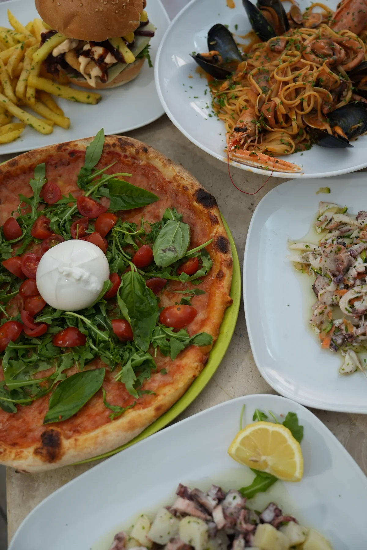 Una tavola Da Frassau con pizza, pasta di mare, panino e antipasti